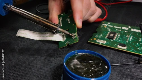Young engineer soldering a board. View from above