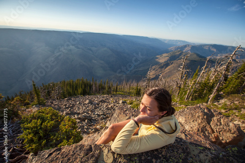 A woman looks out over Hells Canyon at sunset from the Dry Diggins Lookout in the Seven Devil Mountains in central Idaho.  With a 6500+ foot slope to the Snake River at the bottom of the canyon, it is the deepest canyon in North America. photo