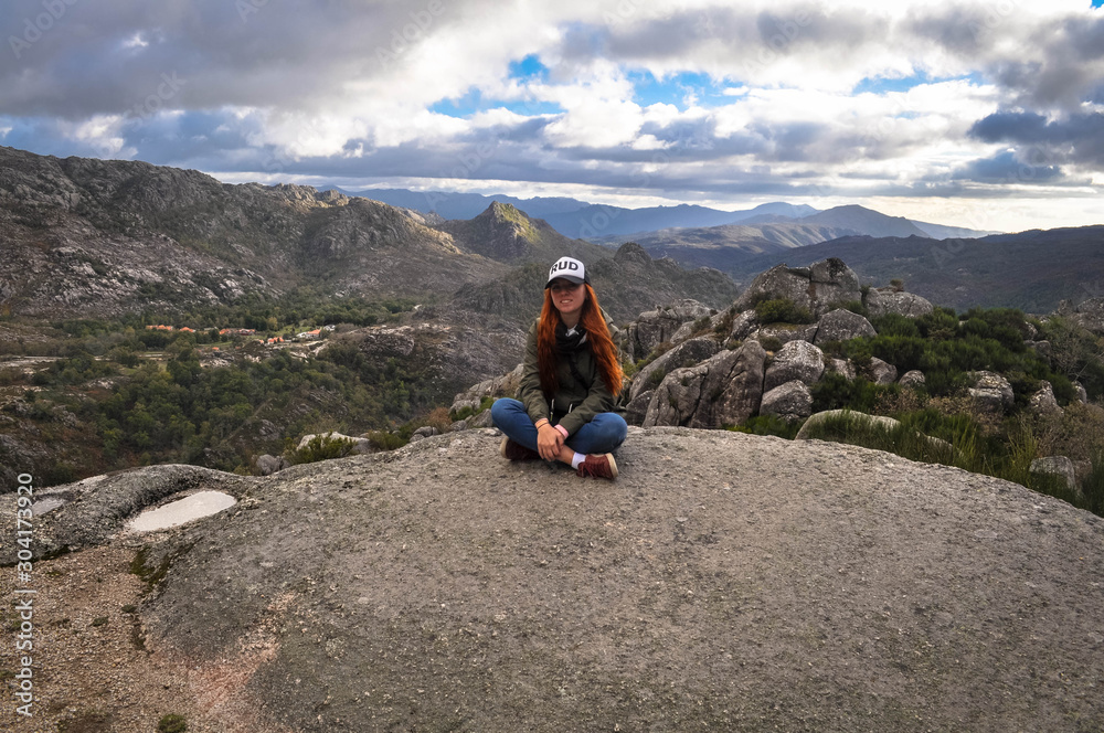Redhead girl in a cap and green jacket at the top of the mountain. Behind the panorama of the mountains . Geres.