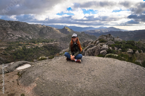 Redhead girl in a cap and green jacket at the top of the mountain. Behind the panorama of the mountains . Geres. © Elena