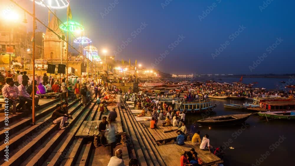 People watching hindu priests performing Agni Puja or Worship of Fire at a ghat in Varanasi day to night time lapse