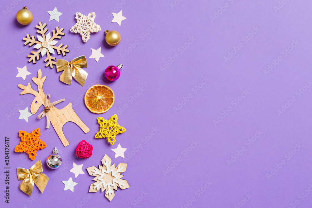 Top view of New Year toys and decorations on purple background. Christmas time concept with empty space for your design Top view of New Year toys and decorations on purple background. Christmas time concept with empty space for your design