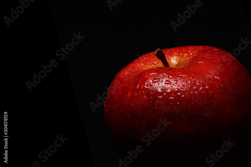 apetyczne-czerwone-jablko-pokryte-kroplami-wody-na-czarnym-tle