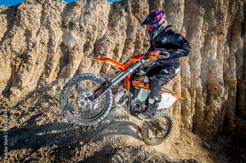 Image of a female dirt biker jumping up a rocky section of trail photo