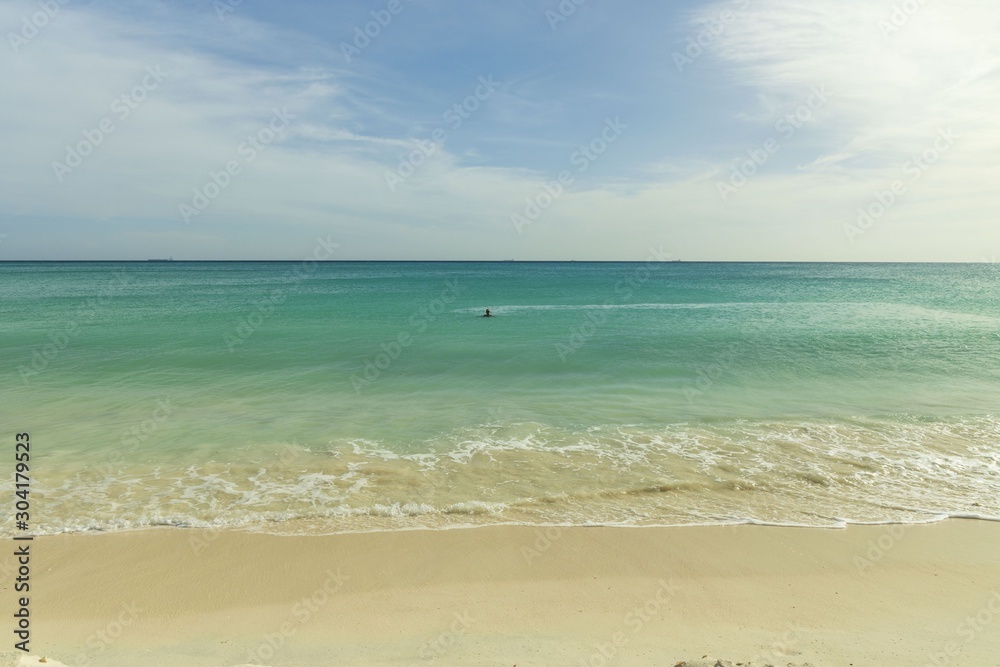 White sand beach and turquoise waves. Turquoise sea water and blue sky. Eagle Beach of Aruba Island.  Beautiful backgrounds.