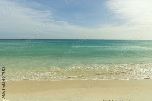 White sand beach and turquoise waves. Turquoise sea water and blue sky. Eagle Beach of Aruba Island. Beautiful backgrounds.