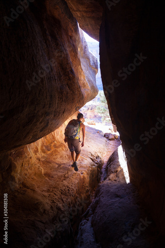 A woman goes through a hidden slot canyon.  part of the 10.8 mile Big Spring Canyon to Elephant Canyon loop in the Needles, Canyonlands National Park. photo