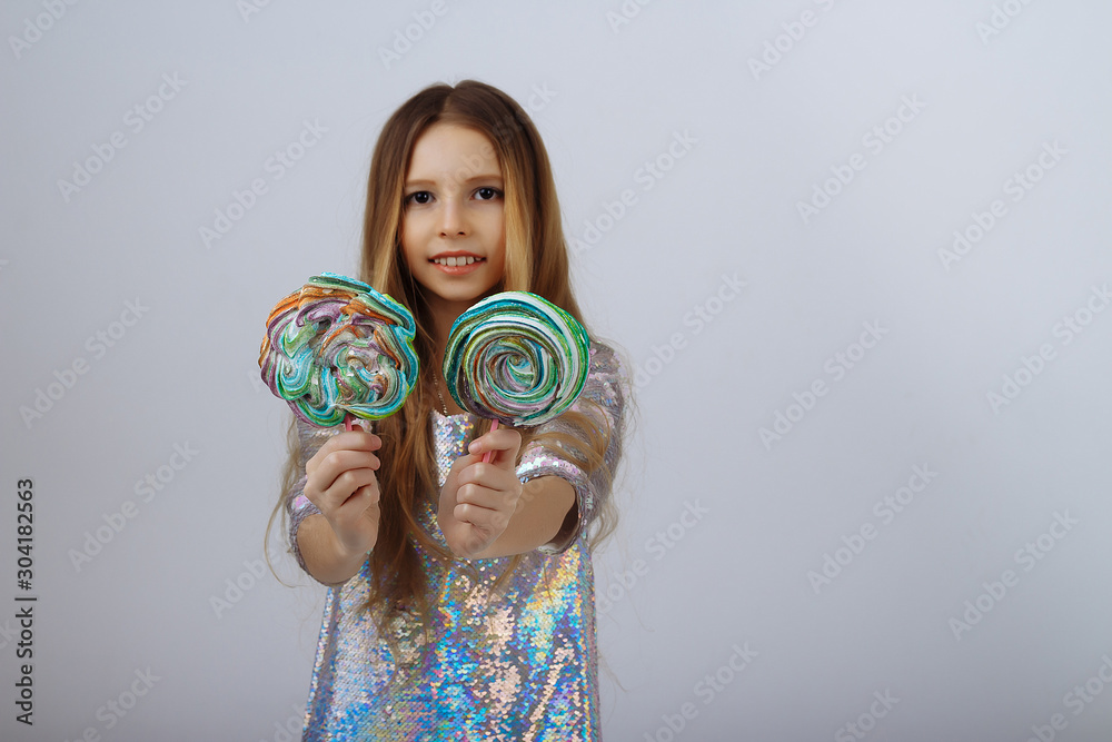 Fototapeta premium beautiful girl smiles and holds a lolly in her hands. a marshmallow long blond hair.