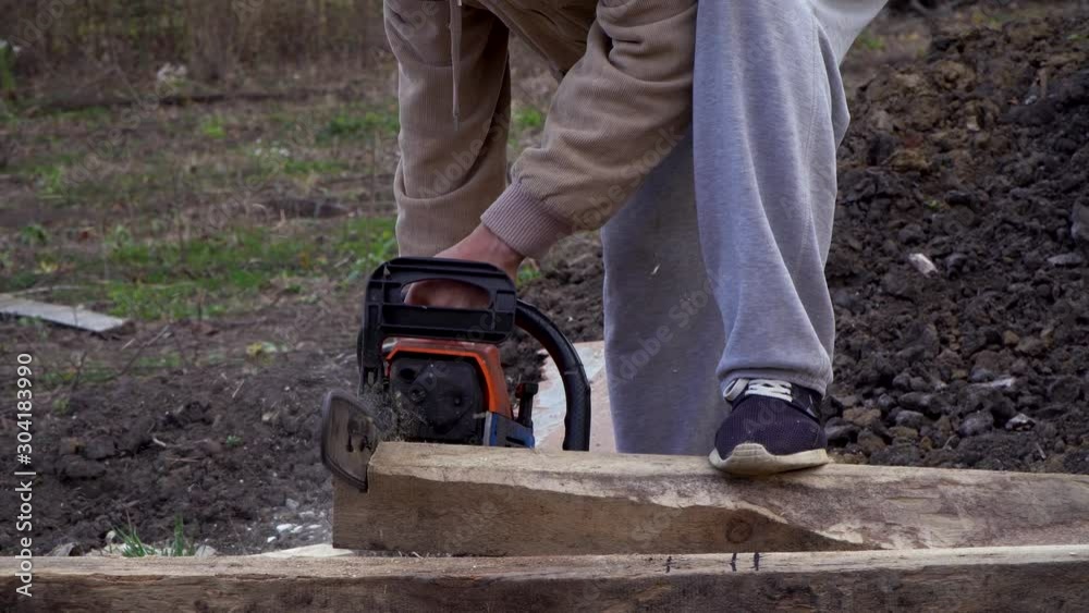 Sawing a wooden board with chainsaw, side view, sawing process, wood sawdust differ in different directionsм Sawing a wooden board with chainsaw, side view, sawing process, wood sawdust differ in different directionsм