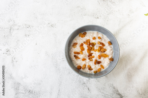 Oatmeal porridge or porridge oats or breakfast cereals with raisins isolated on white marble background. Homemade food. Tasty breakfast. Selective focus. Horizontal photo.