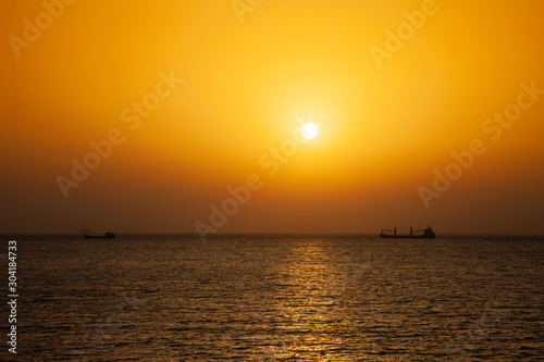 Colorful sunset in the Mediterranean sea with a cargo ship in a distance. View from the deck of a cruise ship © Daniel Fainberg