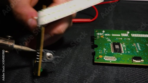 Young engineer soldering a board. View from above