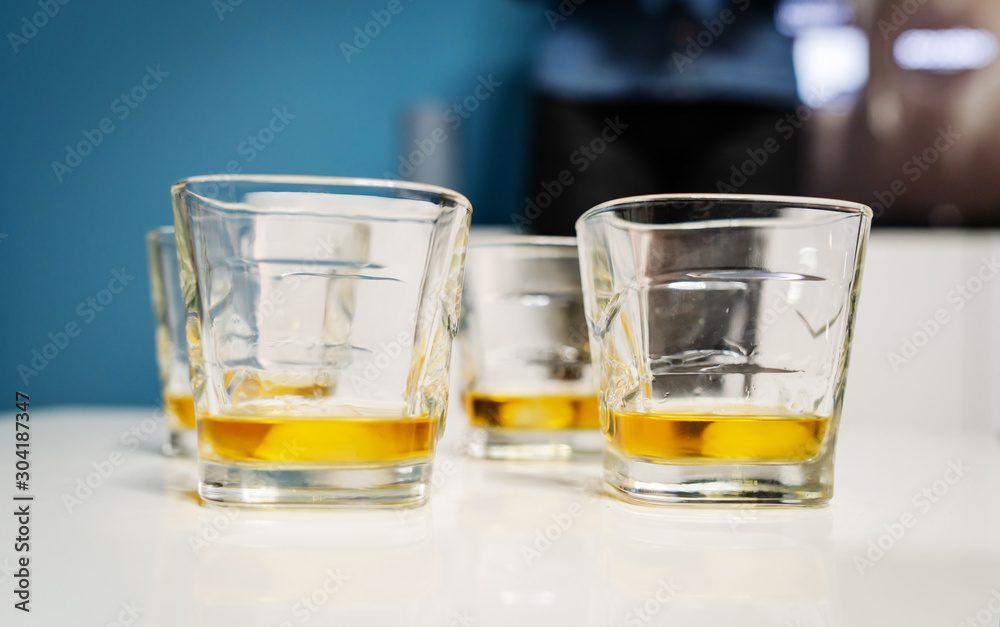 Close up on three glasses whiskey or brandy or cognac alcohol drink on the white table at home Close up on three glasses whiskey or brandy or cognac alcohol drink on the white table at home