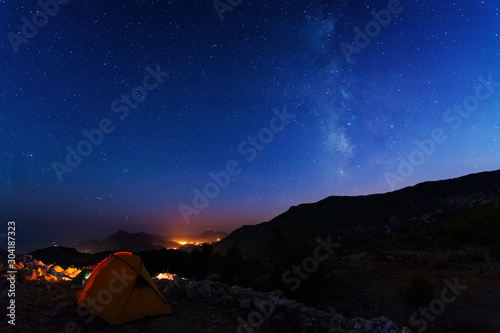 starry night with the Milky Way on the Turkish Mediterranean coast amidst the rocky mountains with tourists in a yellow tent © reme80