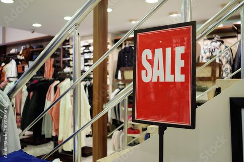 Sale sign on a red background in a clothing store.