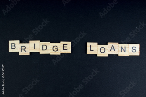 Bridge loans- word composed fromwooden blocks letters on black background, copy space for ad text. photo