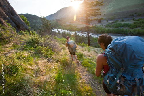 Two woman hike down at sunset from The Bend, one of more than a dozen crags in Tieton Canyon, a climbing area in Washington State. Tieton River is pictured in the background.