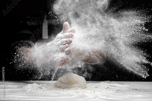 Chef man clap hand and white flour dust on black background