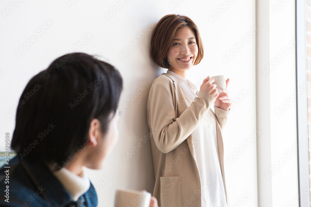 カフェで男性と話す笑顔の20代女性