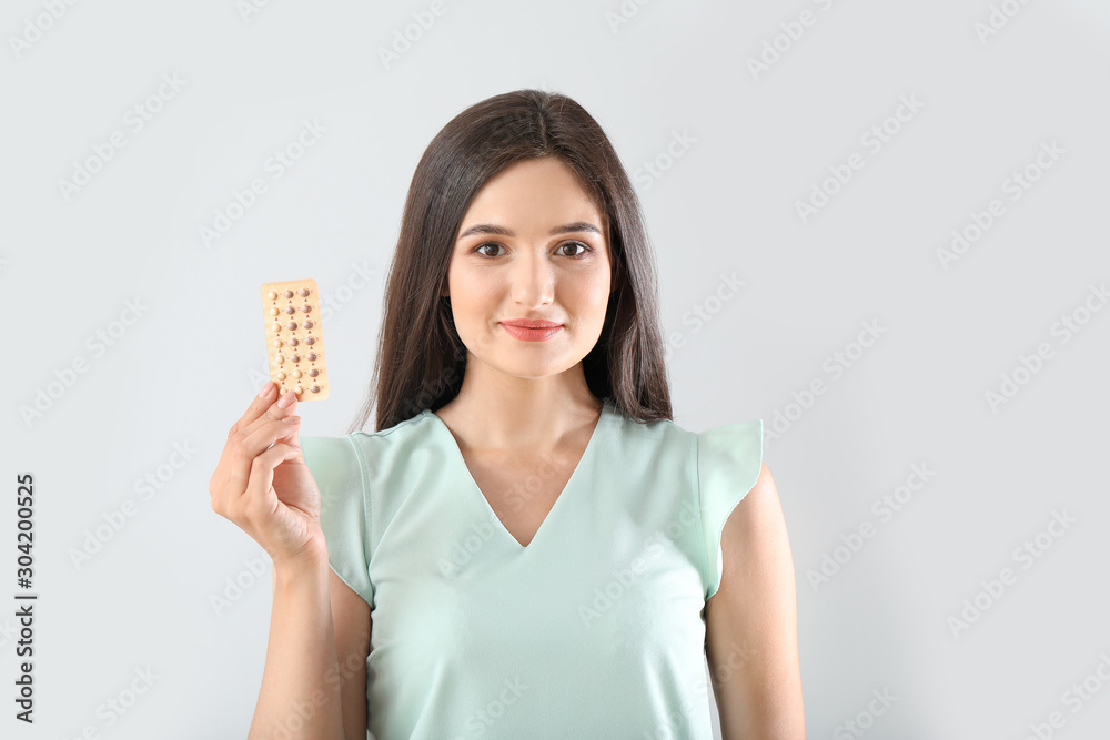 Young woman with pills on light background Young woman with pills on light background