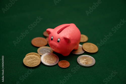 Piggy bank in the form of a pink pig and euro coins and cents on a green background photo