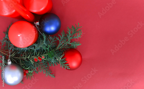 spruce branches with Christmas balls of different colors and a wooden angel on a red background in the corner place for text. concept new year and Christmas