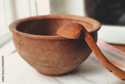 rustic flat lay, clay mortar with wooden pestle for grinding spices on linen background and string of onions on windowsill