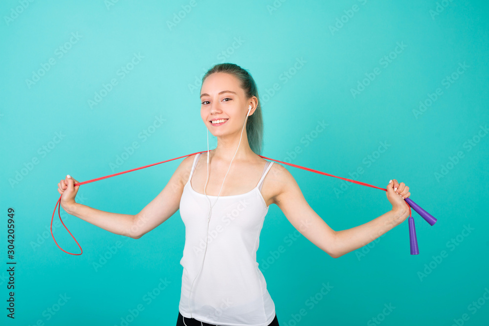 beautiful young slim woman in sportswear on a blue background with a skipping rope in hands beautiful young slim woman in sportswear on a blue background with a skipping rope in hands