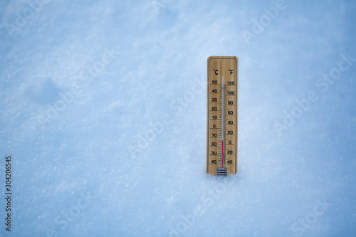Thermometer on snow shows low temperatures in celsius or farenheit.