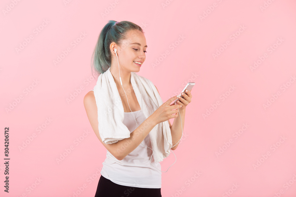 beautiful young slim woman in sportswear on a pink background listens to music beautiful young slim woman in sportswear on a pink background listens to music