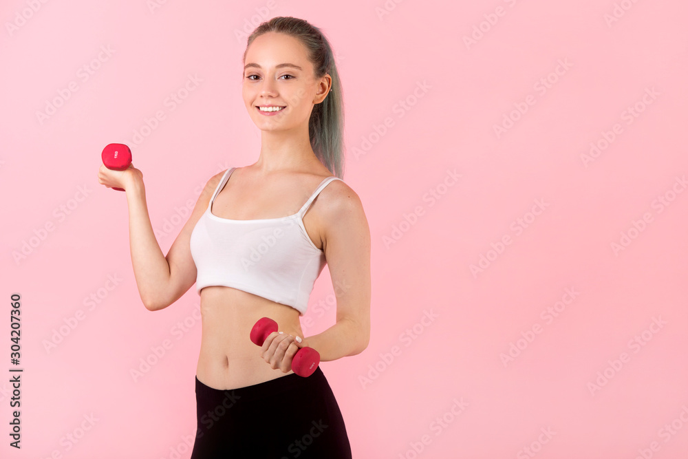 beautiful young woman with dumbbells in hands on pink background beautiful young woman with dumbbells in hands on pink background