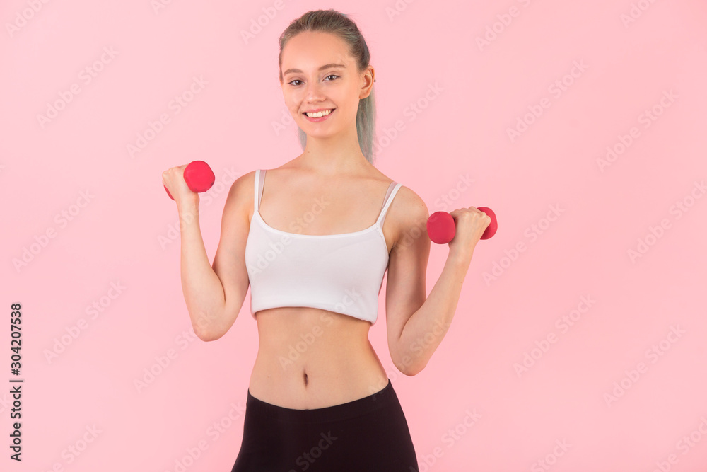 beautiful young woman with dumbbells in hands on pink background beautiful young woman with dumbbells in hands on pink background