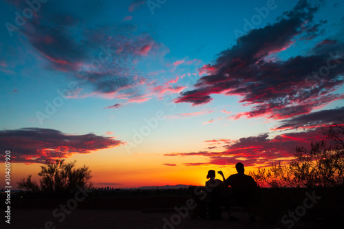 Colorful sky after the sun went down, couple enjoying the scenic nature, taking pictures