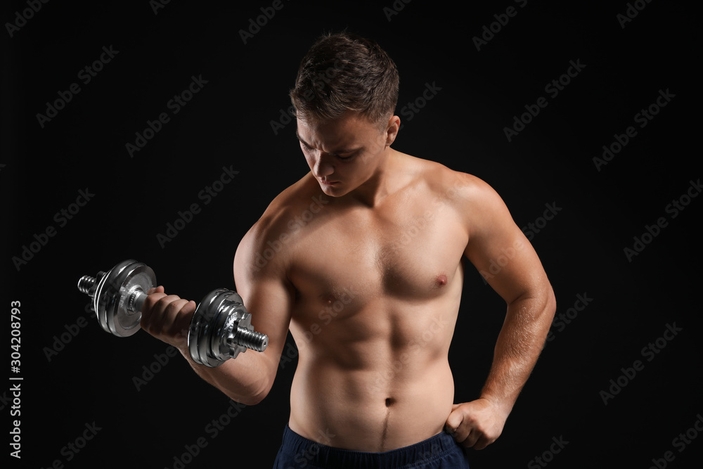 Handsome male bodybuilder with dumbbell on dark background