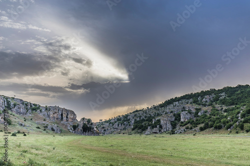 Grey sky over green rocky hills