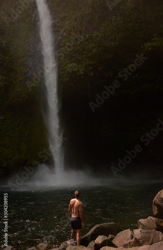 a man contemplates the waterfall La Fortuna, Arenal Volcano National Park, Costa Rica