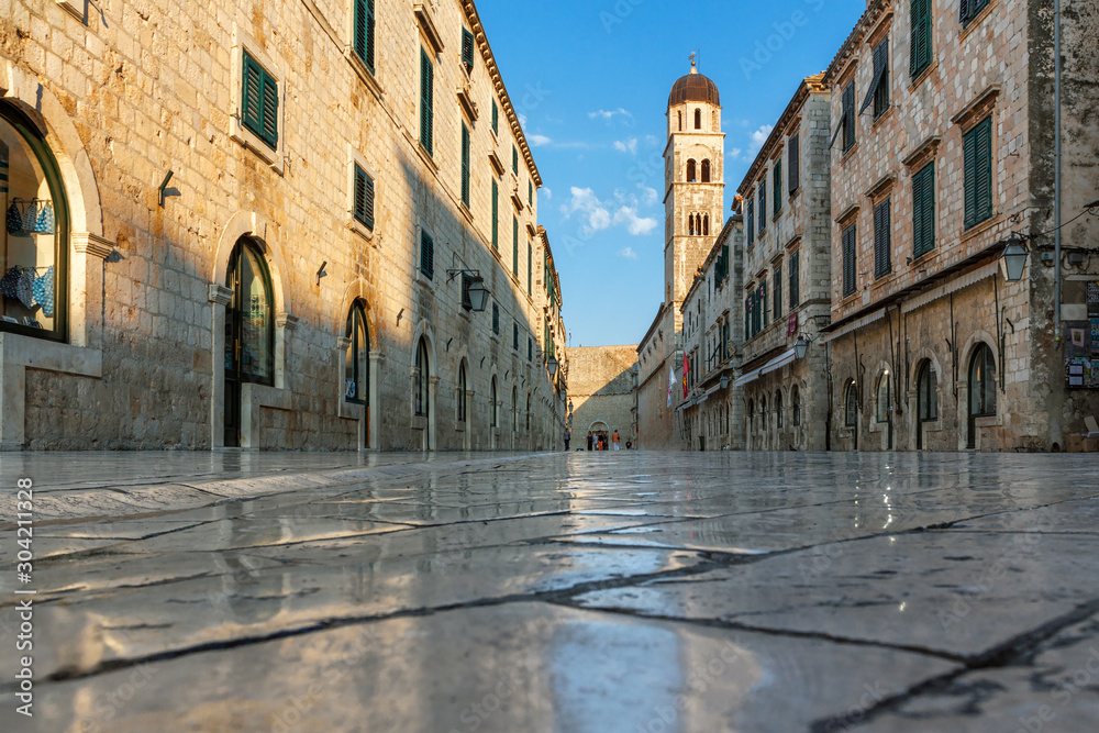 Dubrovnik city, morning sun illuminates an old street, ancient polished tiles glisten