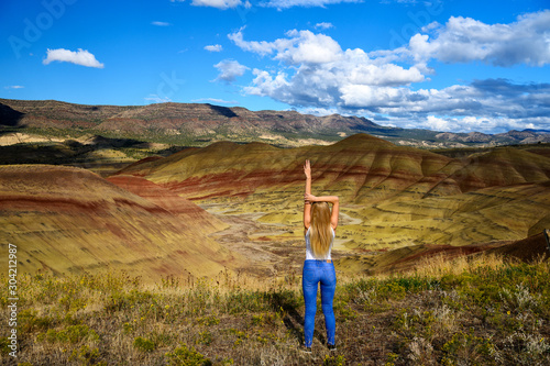 Attractive blond young woman is impressed by the view of the Painted Hills Unit - John Day Fossil Beds National Monument, Oregon, USA photo