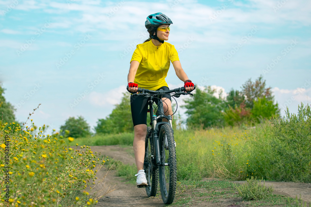 Beautiful girl in yellow riding a bike in nature. Sports and recreation. Hobbies and health. Beautiful girl in yellow riding a bike in nature. Sports and recreation. Hobbies and health.