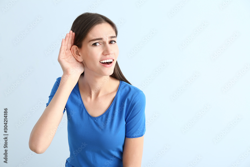 Young woman with hearing problem on color background Young woman with hearing problem on color background