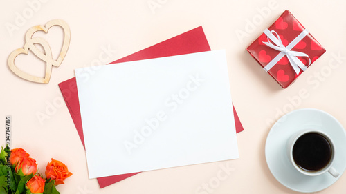 Happy Valentine's Day romantic composition. Top view red craft envelope, blank paper card, git box, rose flowers on pastel beige background. Valentines Day, love, romance concept.