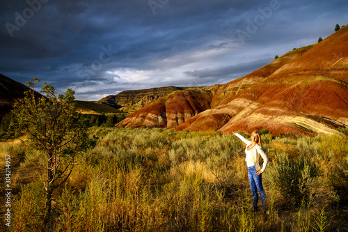 Attractive blond young woman is impressed by the view of the Painted Hills Unit - John Day Fossil Beds National Monument, Oregon, USA photo