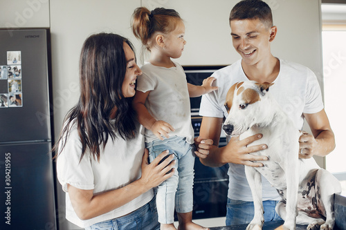 Family in a kitchen. Little girl with a dog. Mother and father in a white t-shirts