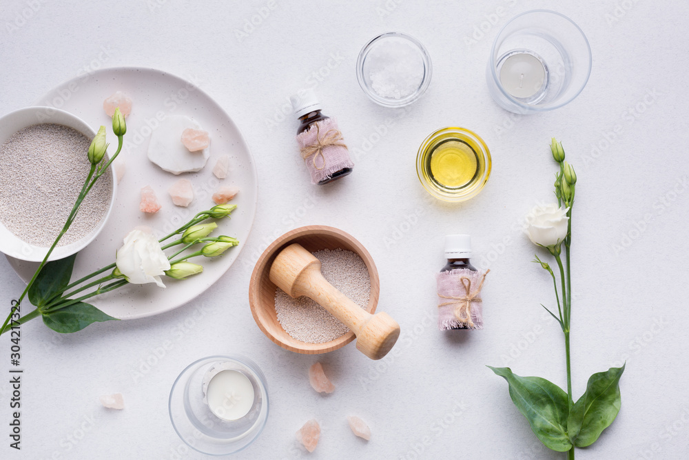 Spa composition with oils, sea salt, candles and a branch of white eustoma on a white background