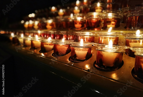 Candles in a church, cathedral or temple, in yellow transparent candlesticks. The concept of mourning. We remember, we grieve. Selective focus, side view, copy space
