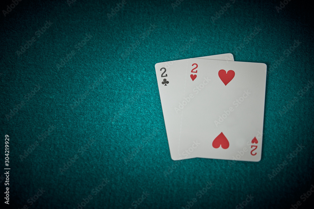 Two cards of trebles and two of hearts on a green carpet of poker game. Superios view.