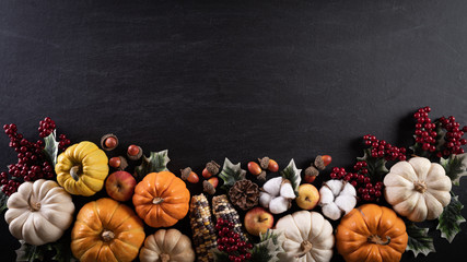 Top view of  Autumn maple leaves with Pumpkin and red berries on black wooden background. Thanksgiving day concept.