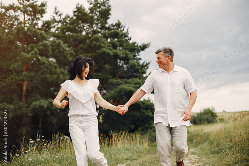 Adult couple in a summer field. Handsome senior in a white shirt. Woman in a white blouse © hetmanstock2