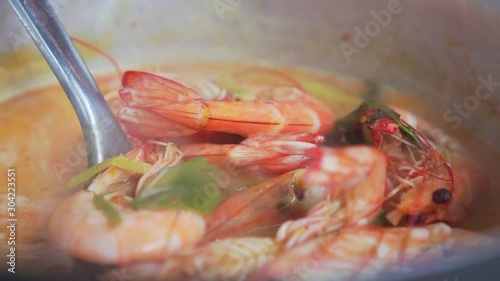 Someone stirring up Spicy Soup with Prawn in a pot. Boiled soup. Tom Yum Goong. Thai Food. Pan shot Slow Motion