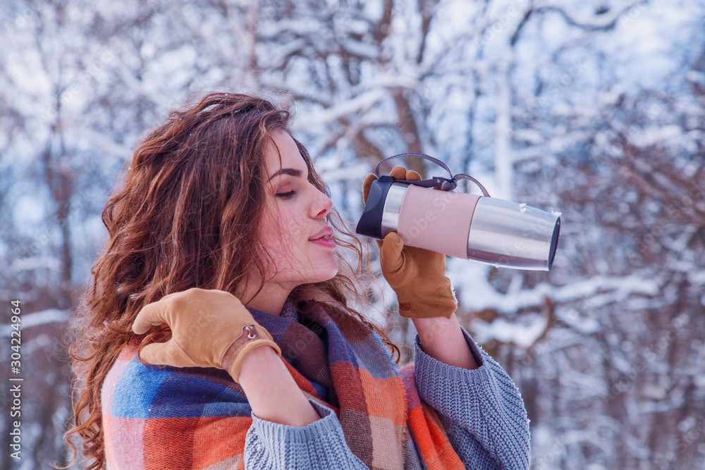 Beauutiful young woman warming up with hot tea or coffee outdoors in winter. Beauutiful young woman warming up with hot tea or coffee outdoors in winter.